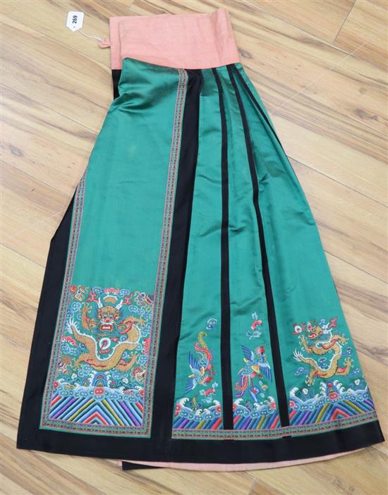 A late 19th century green silk satin Chinese skirt, embroidered in polychrome silks with gold coloured dragon symbols, lined in pink si